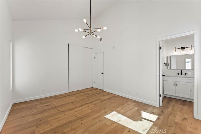 unfurnished dining area with baseboards, a notable chandelier, a sink, and light wood-style floors