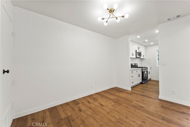 interior space with visible vents, baseboards, wood finished floors, and a chandelier
