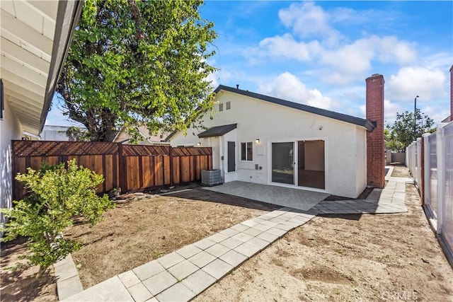 back of property with a fenced backyard, stucco siding, a chimney, and a patio area