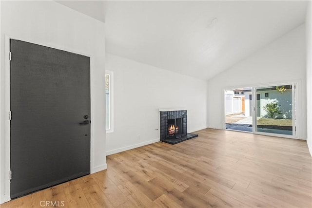 unfurnished living room featuring baseboards, a brick fireplace, wood finished floors, and high vaulted ceiling