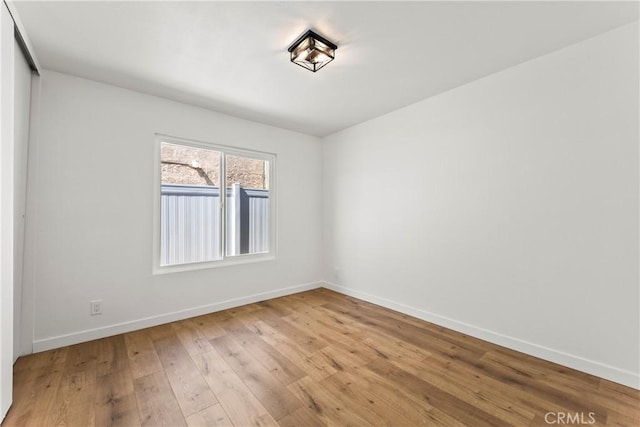 spare room with baseboards and wood finished floors
