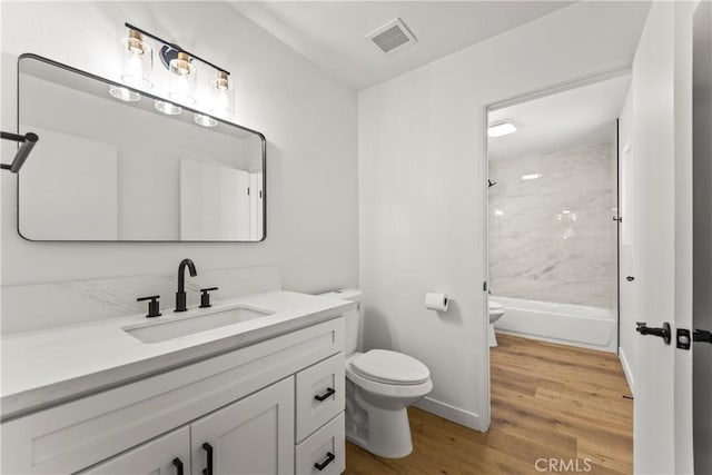 bathroom with vanity, toilet, tub / shower combination, wood finished floors, and visible vents