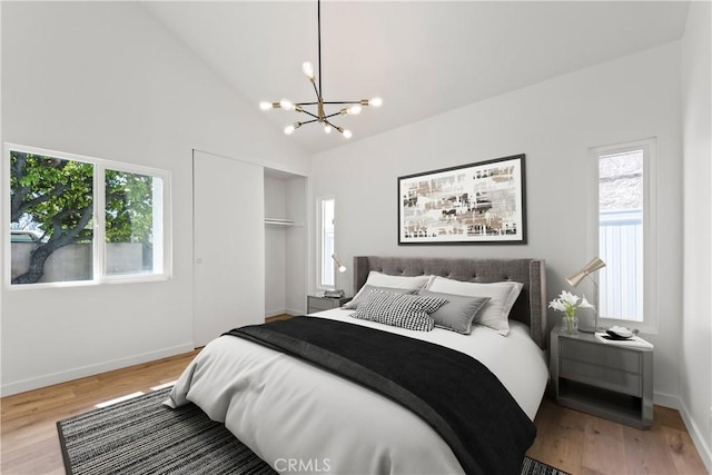 bedroom with a closet, baseboards, wood finished floors, and a notable chandelier