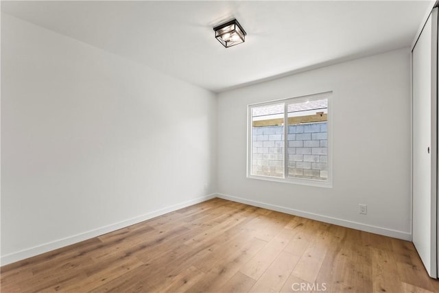 unfurnished room featuring baseboards and light wood-type flooring