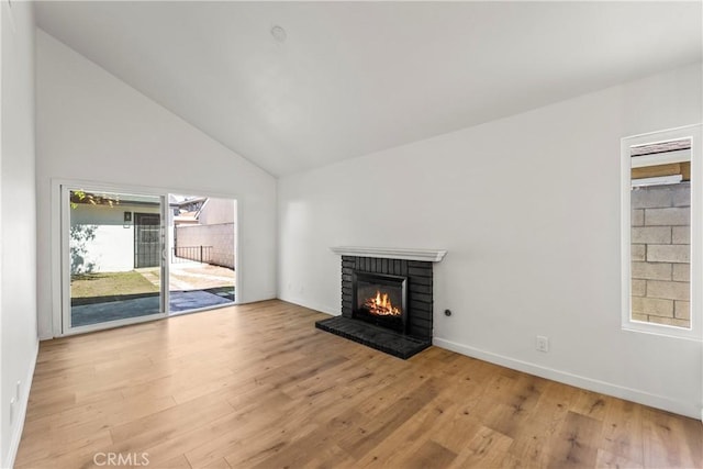 unfurnished living room featuring wood finished floors, baseboards, a brick fireplace, and lofted ceiling