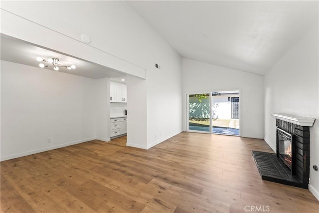 unfurnished living room featuring a brick fireplace, high vaulted ceiling, light wood-style flooring, baseboards, and visible vents