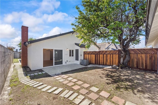 back of property featuring a chimney, central AC, a fenced backyard, a patio, and stucco siding