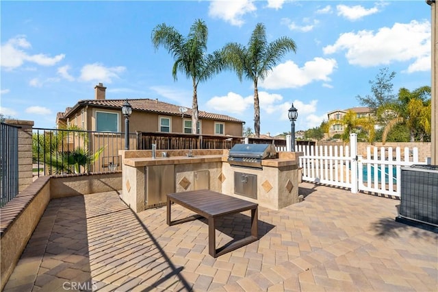 view of patio with exterior kitchen, grilling area, and fence