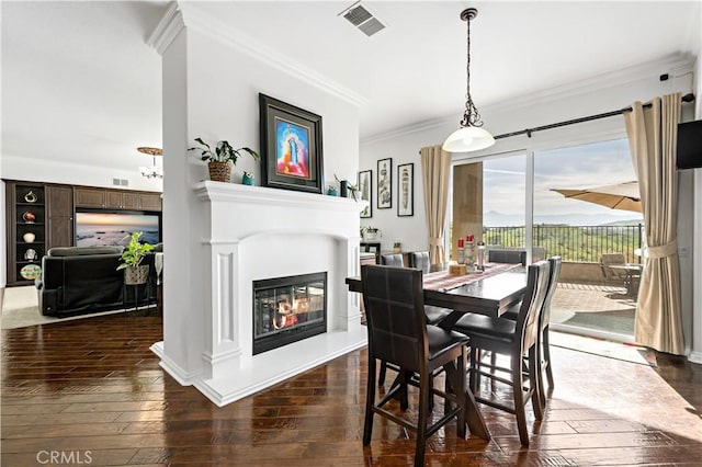 dining space with visible vents, ornamental molding, a glass covered fireplace, and dark wood-style floors