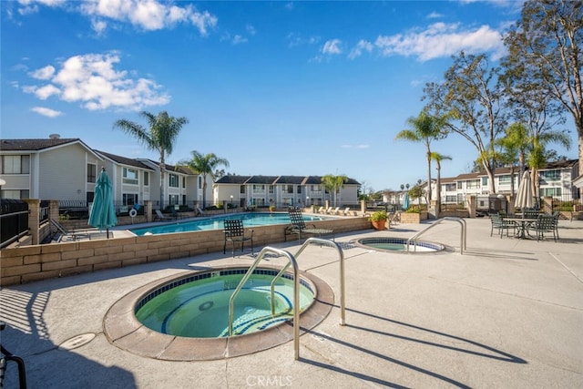 community pool featuring a hot tub, a residential view, and a patio area