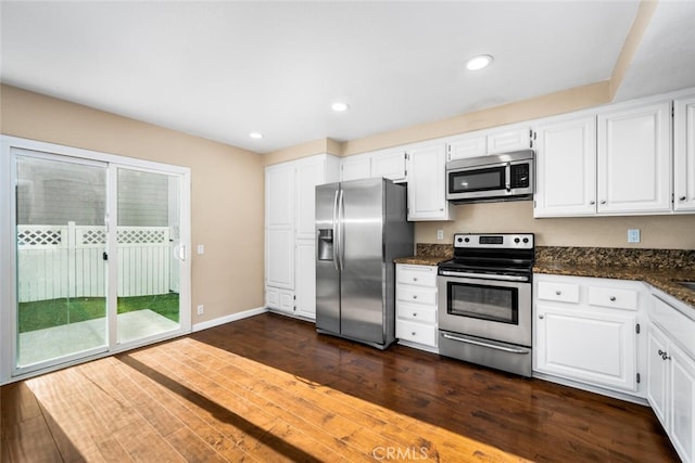 kitchen with appliances with stainless steel finishes, dark wood finished floors, dark stone counters, white cabinetry, and recessed lighting