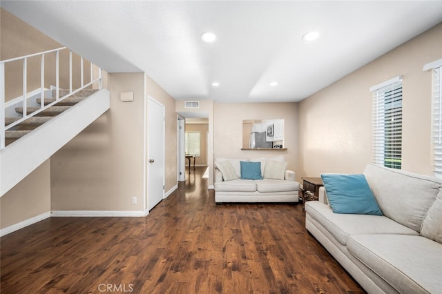 living area with visible vents, baseboards, wood finished floors, and a wealth of natural light