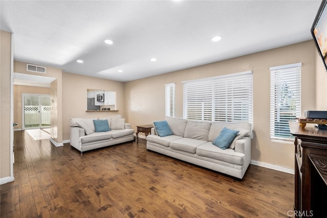 living room with dark wood-style flooring, baseboards, visible vents, and recessed lighting