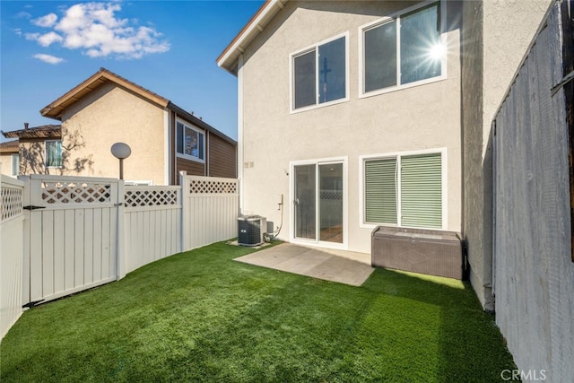 rear view of house with fence, stucco siding, cooling unit, a patio, and a yard