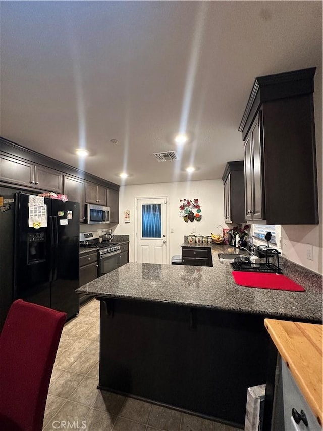 628 Marcus St, Merced, CA 95341 - kitchen featuring visible vents, a peninsula, a kitchen breakfast bar, tile patterned floors, and stainless steel appliances