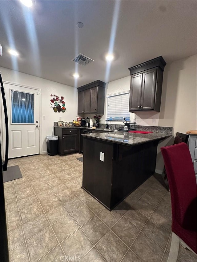 628 Marcus St, Merced, CA 95341 - kitchen with a kitchen breakfast bar, visible vents, tile patterned flooring, a peninsula, and dark stone counters