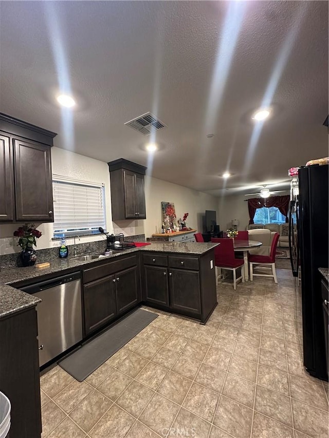 628 Marcus St, Merced, CA 95341 - kitchen with visible vents, freestanding refrigerator, a peninsula, dark stone countertops, and dishwasher