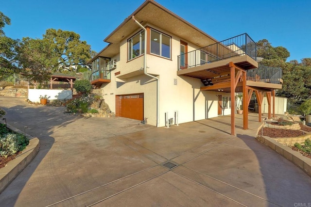 view of home's exterior featuring a garage, stucco siding, concrete driveway, and a balcony