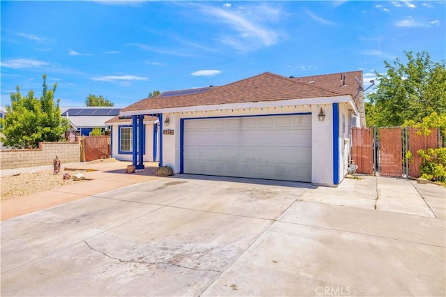 ranch-style house with roof with shingles, fence, stucco siding, roof mounted solar panels, and a gate