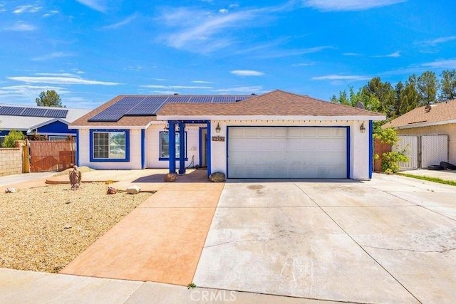 single story home with concrete driveway, fence, roof mounted solar panels, and a garage