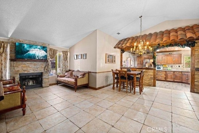 dining room featuring a notable chandelier, light tile patterned flooring, vaulted ceiling, and a fireplace