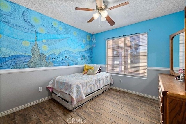 bedroom featuring baseboards, a textured ceiling, ceiling fan, and wood finished floors