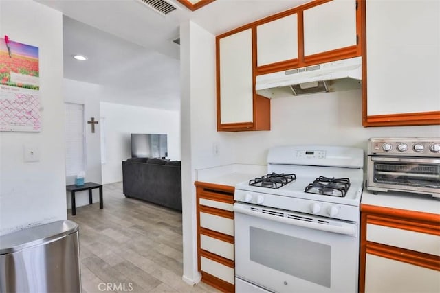 3514 Myers St Unit 15, Riverside, CA 92503 - kitchen with white gas stove, under cabinet range hood, light countertops, light wood-type flooring, and white cabinets