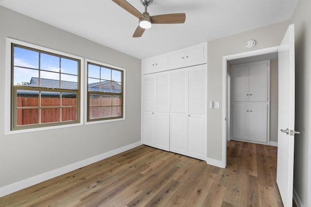 unfurnished bedroom featuring baseboards, a ceiling fan, a closet, and hardwood / wood-style floors