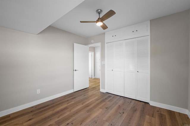 unfurnished bedroom with baseboards, ceiling fan, wood finished floors, and a closet