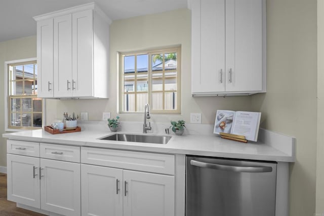 kitchen with stainless steel dishwasher, a sink, white cabinets, and a healthy amount of sunlight