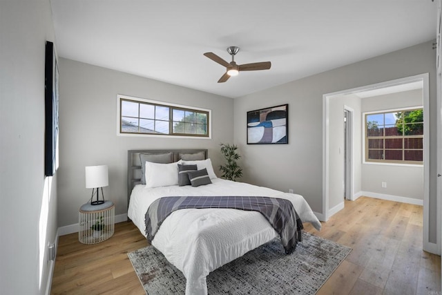 bedroom with a ceiling fan, baseboards, and light wood-style flooring