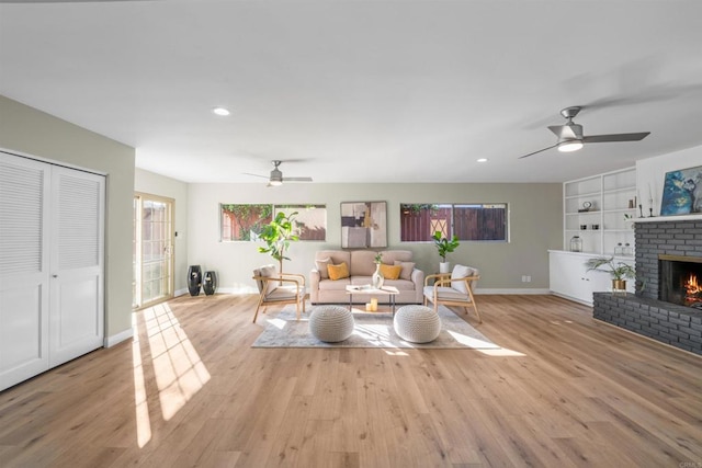 living room featuring ceiling fan, a brick fireplace, baseboards, recessed lighting, and light wood-style flooring