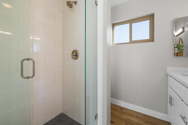 full bath with vanity, baseboards, wood finished floors, and a shower stall