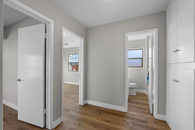 corridor with baseboards and wood finished floors