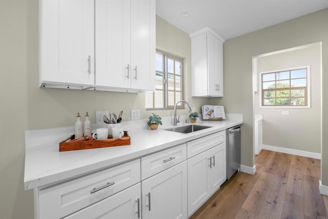 kitchen with a sink, a wealth of natural light, light wood-type flooring, and dishwasher