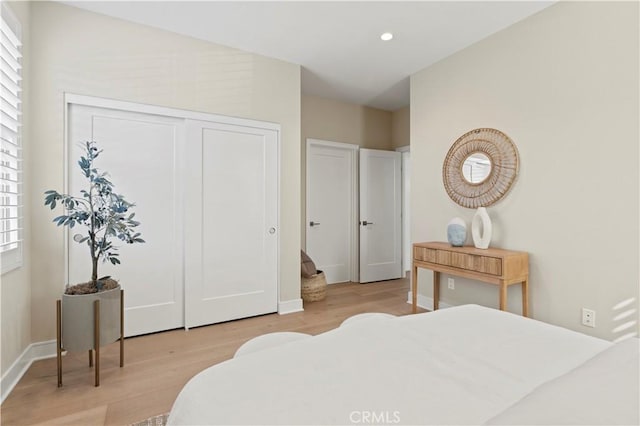 bedroom featuring baseboards, a closet, recessed lighting, and light wood-style flooring