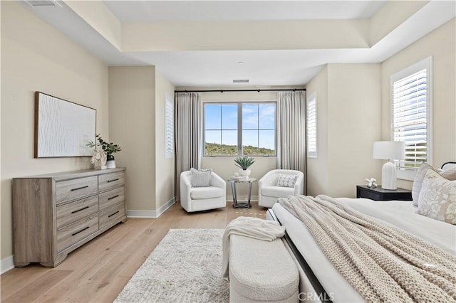 bedroom featuring baseboards, multiple windows, and light wood-type flooring