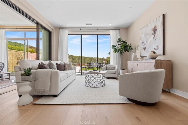 living area with recessed lighting, baseboards, wood finished floors, and a wealth of natural light