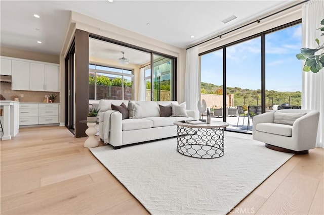 living room with recessed lighting, a wealth of natural light, light wood finished floors, and visible vents