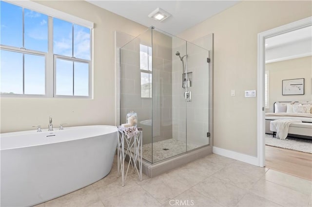 ensuite bathroom with a freestanding tub, tile patterned floors, a shower stall, and ensuite bath