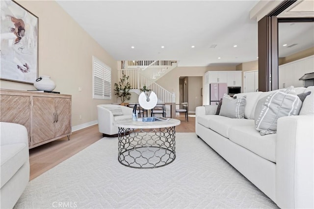 living room with baseboards, recessed lighting, light wood-style flooring, and stairs