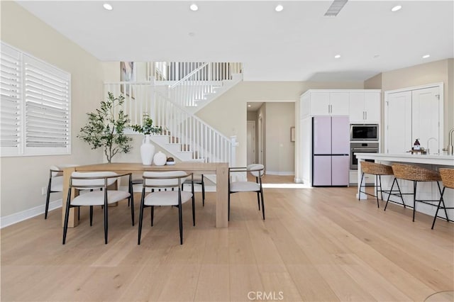 dining area featuring recessed lighting, baseboards, light wood-style flooring, and stairway