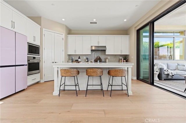 kitchen featuring white refrigerator, built in microwave, under cabinet range hood, white cabinetry, and oven