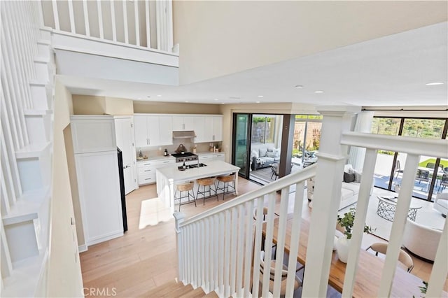 stairs with a high ceiling, recessed lighting, and wood finished floors
