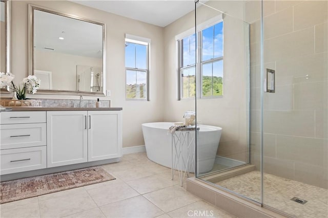 full bathroom with vanity, a freestanding tub, baseboards, tile patterned floors, and a stall shower