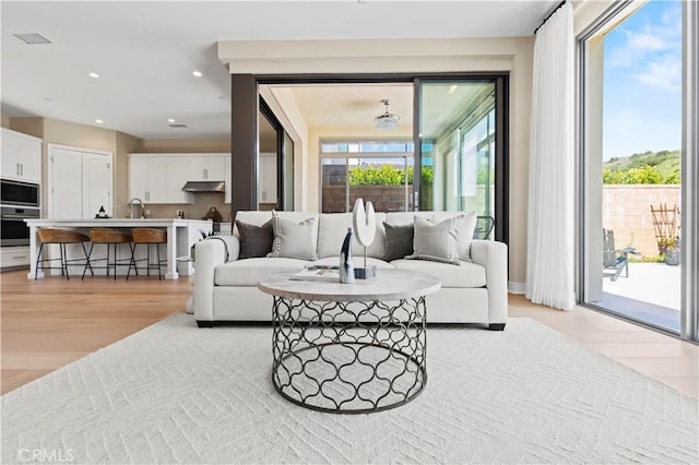 living area with recessed lighting, visible vents, a healthy amount of sunlight, and light wood-type flooring