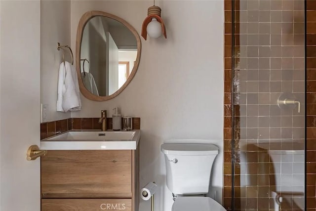 bathroom featuring vanity, toilet, and tiled shower