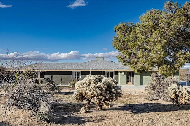 rear view of property with a garage and stucco siding