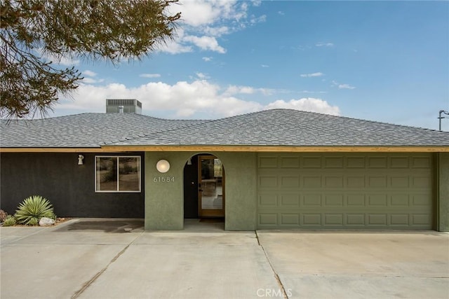 61584 Pueblo Trl, Joshua Tree, CA 92252 - view of front facade featuring central AC, stucco siding, a shingled roof, and a garage