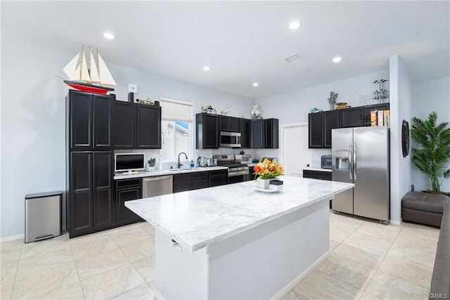 68245 Peladora Rd, Cathedral City, CA 92234 - kitchen featuring appliances with stainless steel finishes, light stone counters, a sink, dark cabinetry, and a kitchen island